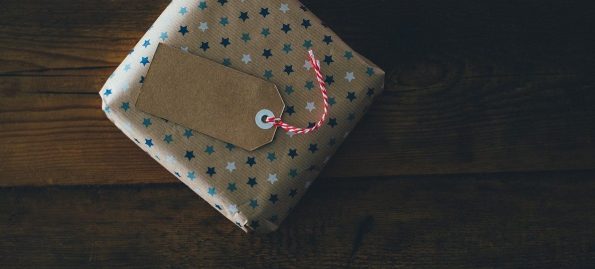 A gift wrapped in polka dotted paper sits on a wooden surface