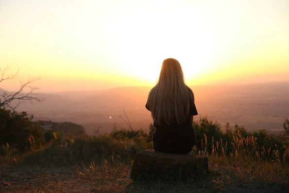 Girl watching sunset from the top of a hill